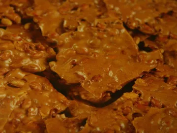 Куски арахисового грильяжа в янтарной карамели крупным планом