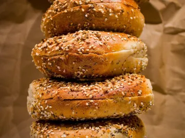Стопка бейглов с маком, кунжутом и сушёным луком на бумаге