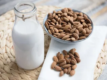 Миндальное молоко в бутылке и миндаль в миске