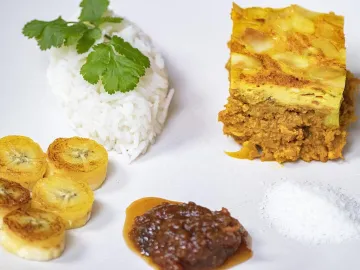 Кусок боботи с рисом, жареным бананом и чатни на тарелке
