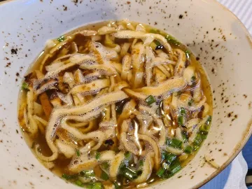 Бульон с нарезанными полосками блинчиками и шнитт-луком в тарелке