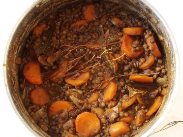 Тушёная зелёная чечевица с морковью и лавровым листом в кастрюле