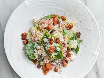 Салат с беконом, яйцом, авокадо и сыром на белой тарелке