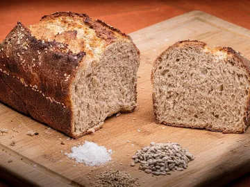 Цельнозерновой хлеб на разделочной доске рядом с семечками