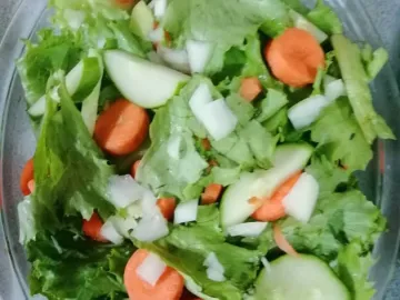 Листовой салат, огурцы и морковь в стеклянной миске