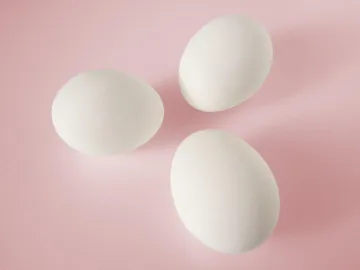 Три белых куриных яйца на розовом фоне