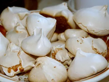 Горка белых домашних безе на тарелке