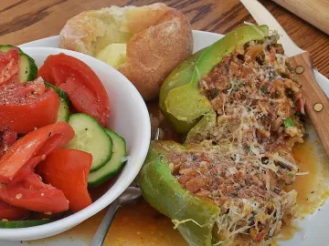 Фаршированные зелёные перцы с мясом и рисом на тарелке с салатом