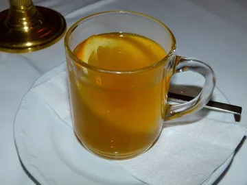 Белый глинтвейн с долькой апельсина в стеклянной кружке
