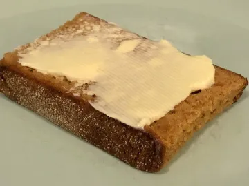 Ломоть голландской пряничной коврижки со сливочным маслом на тарелке