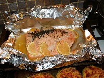 Кусок запечённой красной рыбы с лимоном и розмарином в фольге