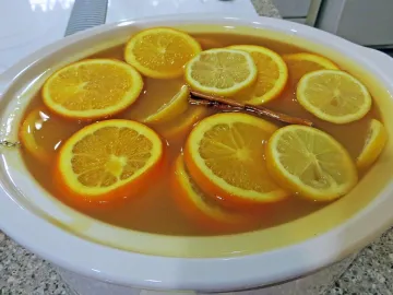 Горячий яблочный пунш с кружками апельсина, лимона и корицей