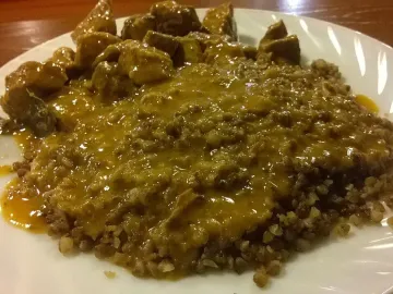 Гречка с кусочками говядины и густой подливой на белой тарелке