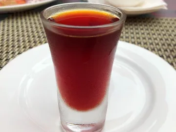 Рюмка калгановки красно-коричневого цвета на тарелке