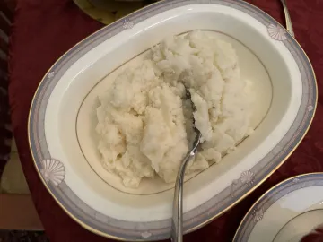 Картофельное пюре в овальной сервировочной миске с ложкой