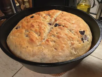 Круглый хлеб с оливками в чугунной форме, золотистая корка