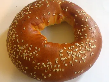 Румяный бублик с кунжутом на светлом фоне