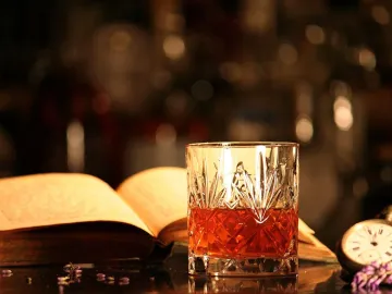 Коктейль Сазерак в хрустальном стакане рядом с книгой