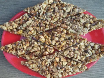 Козинаки из грецких орехов ромбами на красной тарелке