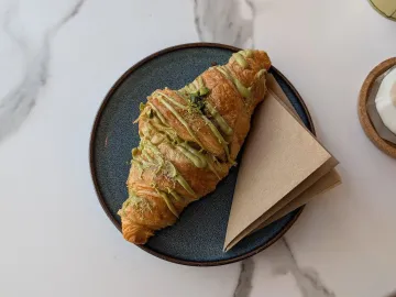 Круассан с фисташковым кремом и рублеными фисташками на тарелке