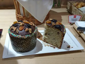 Пасхальный кулич с шоколадной глазурью, орехами и сухофруктами, рядом отрезанный кусок