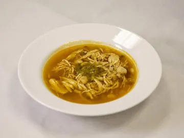 Куриный суп с белой фасолью и зеленью в белой тарелке