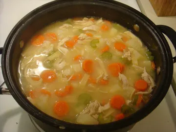 Куриный суп с домашней лапшой, морковью и сельдереем в кастрюле