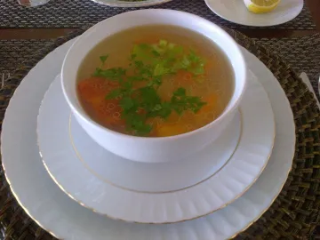 Прозрачный куриный суп с морковью и зеленью в белой миске