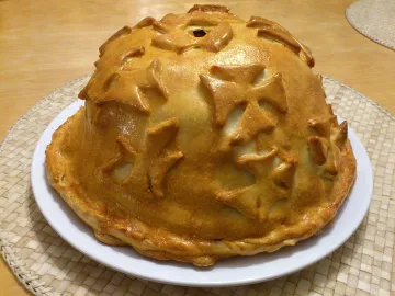 Высокий курник с куполом и украшениями из теста на тарелке