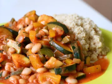 Кус-кус с рагу из кабачка, перца и белой фасоли на салатовой тарелке