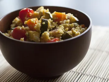 Кускус с кабачком, морковью и помидорами черри в коричневой миске