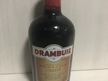 Бутылка шотландского медового ликёра Drambuie на светлом фоне