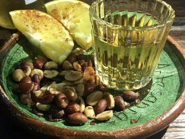 Рюмка мескаля с дольками апельсина и жареным арахисом