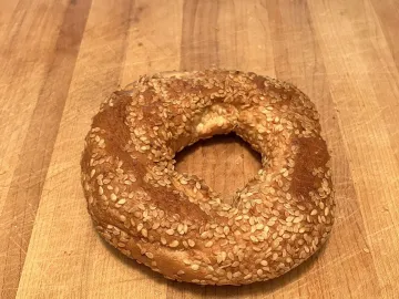 Монреальский бейгл, густо покрытый кунжутом, на деревянной доске