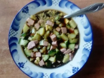 Окрошка на квасе с колбасой и огурцами в тарелке