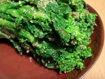 Зелёные овощи, посыпанные кунжутным соусом гомаэ, на коричневой тарелке