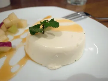 Белая панакота с веточкой мяты на белой тарелке