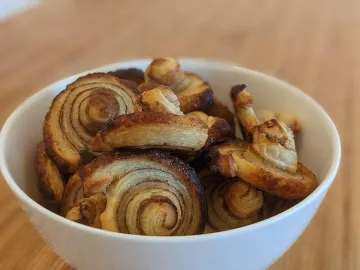 Слоёное печенье ушки с корицей и карамелью в белой миске