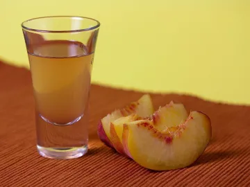 Рюмка персикового шнапса и дольки свежего персика