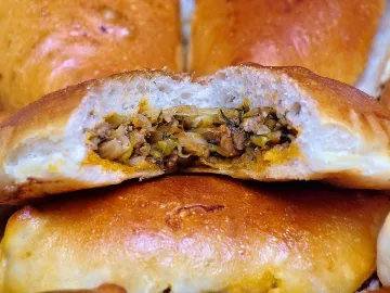 Разломленный румяный пирожок с мясом и капустой