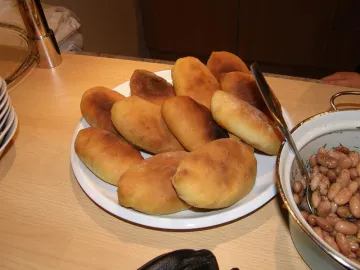 Пирожки на белой тарелке рядом с фасолью