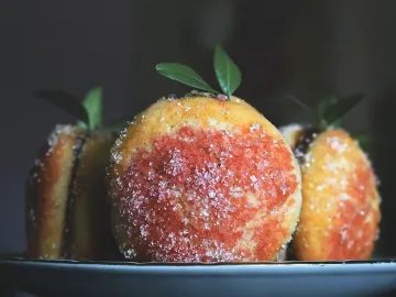 Пирожные персики в сахаре с листиками на тарелке