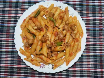 Паста пенне с курицей и томатным соусом на тарелке