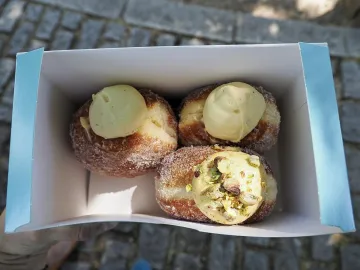 Три пончика в сахаре с фисташковым кремом в картонной коробке