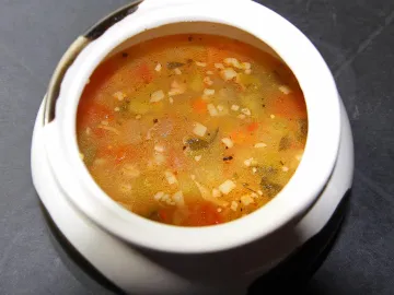 Тарелка рассольника с перловкой, морковью и огурцами в белом горшочке