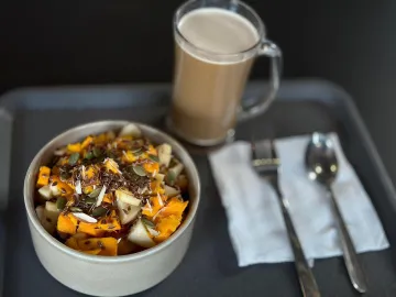 Миска с кусочками тыквы, груши и семенами рядом с кофе