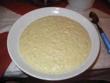 Густая пшённая каша на молоке в белой тарелке