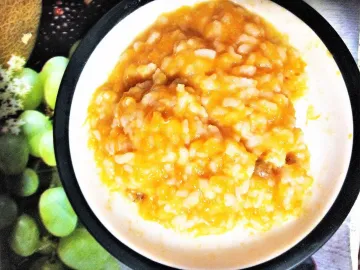 Рисовая каша с тыквой и изюмом в белой тарелке