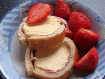 Кусочки рулета с мороженым и джемом рядом с клубникой