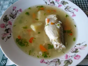 Рыбный суп с куском рыбы, картофелем, морковью и укропом в тарелке